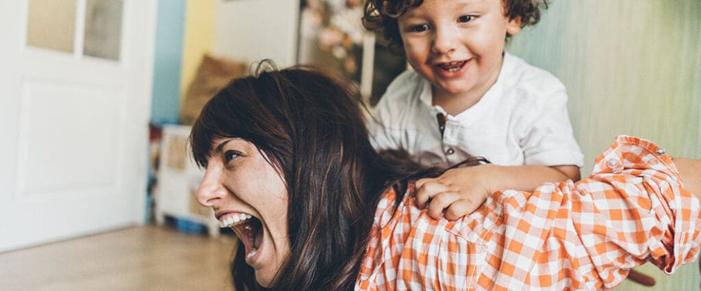 Beautiful young mother having fun at home with her cute little son