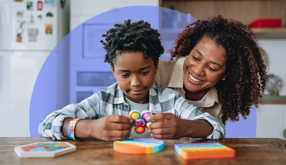 Woman working one-on-one with a child with autism, using visual aids and supportive gestures to encourage communication and learning
